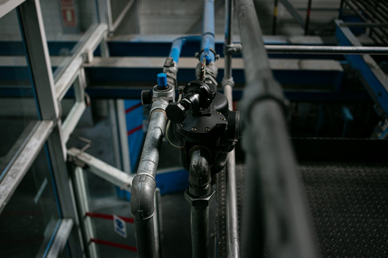 About Detailed view of a metallic pipe system with valves in an industrial setting.