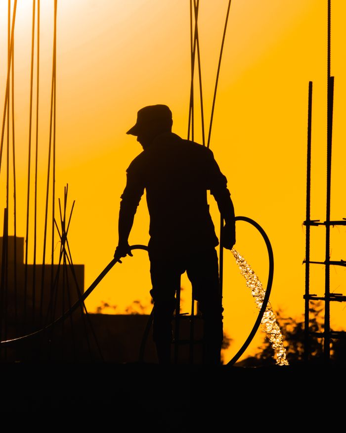 creative-02 Silhouette of a construction worker standing on a building site at sunset.
