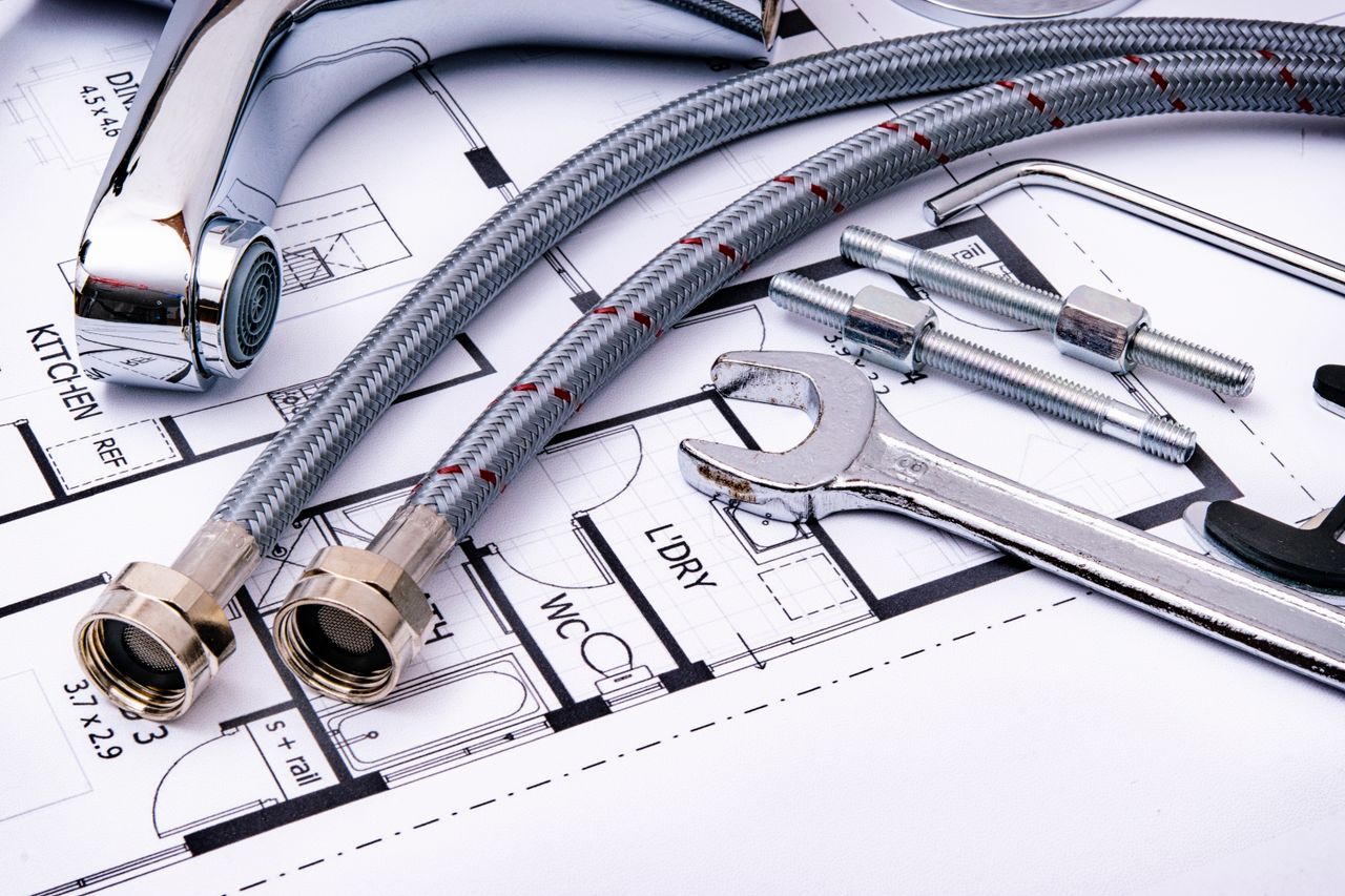 creative-03 Close-up of plumbing tools and faucet on top of an architectural blueprint, perfect for hardware and construction themes.