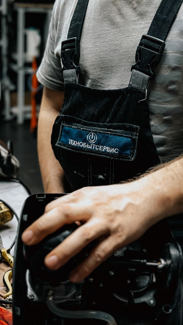 creative-03 Close-up of mechanic in overalls fixing an appliance, showcasing precision in a workshop setting.