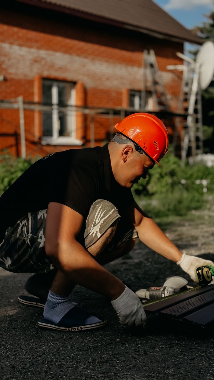 digital-01 A construction worker wearing a hard hat working with tools outside a building.