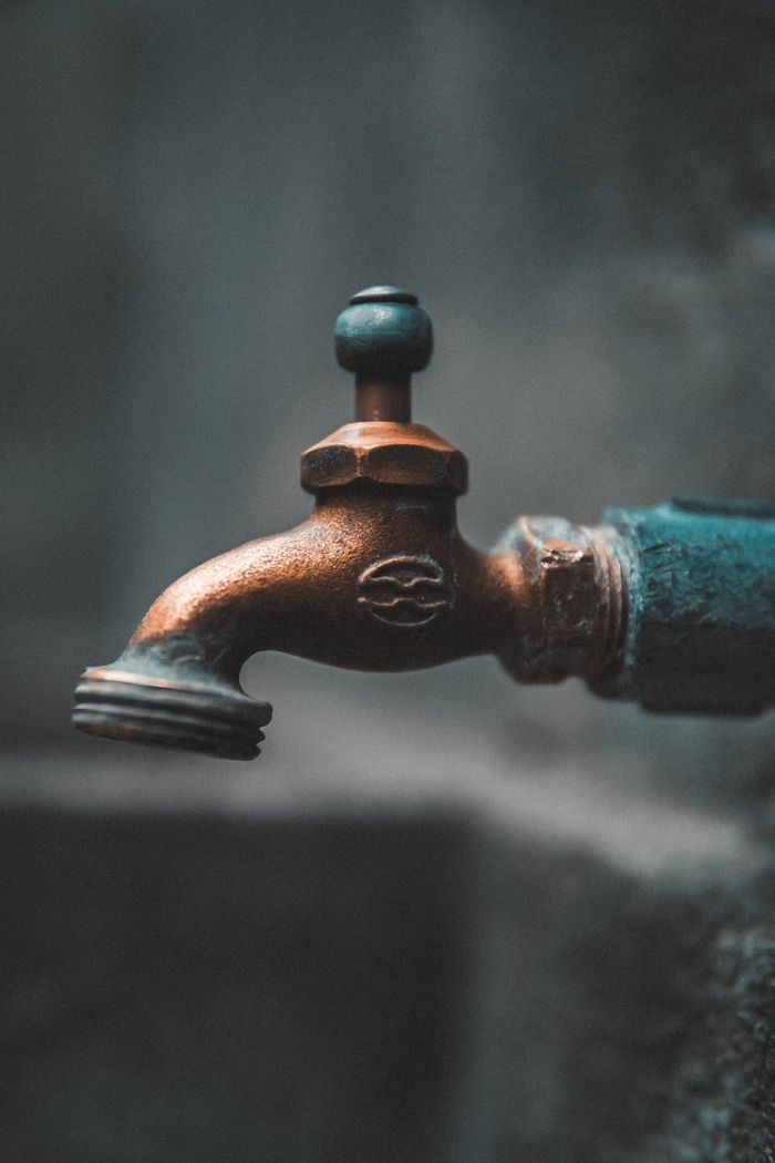mobile-02 Detailed close-up of a rustic metal faucet outdoors with soft focus background.