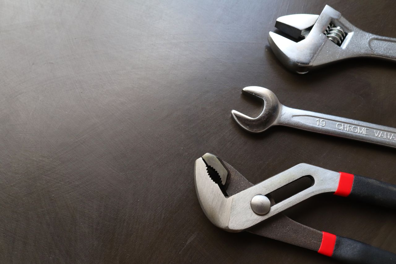 creative-03 High-quality image of various metal tools including wrenches and pliers arranged on a dark surface.